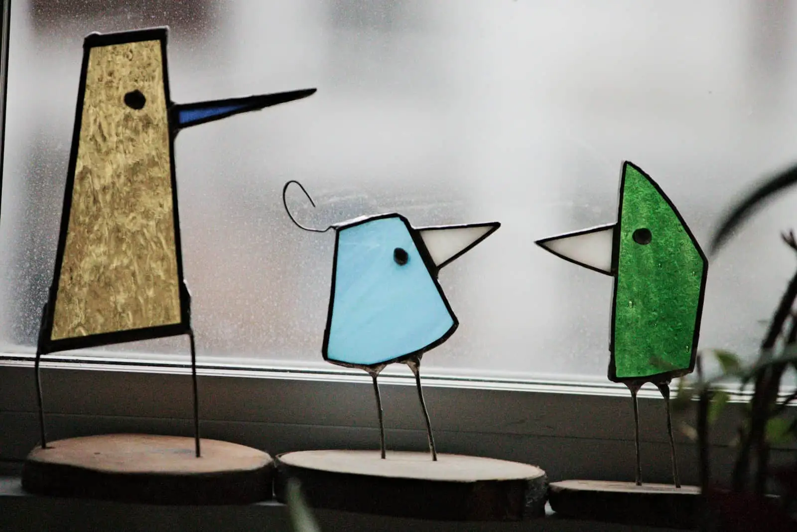 Trois oiseaux posés sur le rebord d’une fenêtre