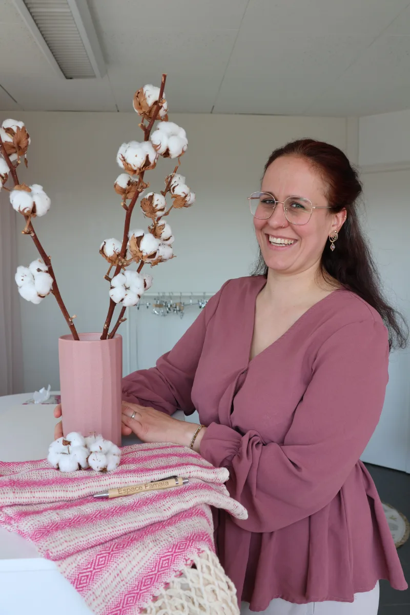 Christine Grandjean, co-fondatrice de l'Espace Famaïa, souriante près d'un vase de branches de coton et d'un Rebozo rose